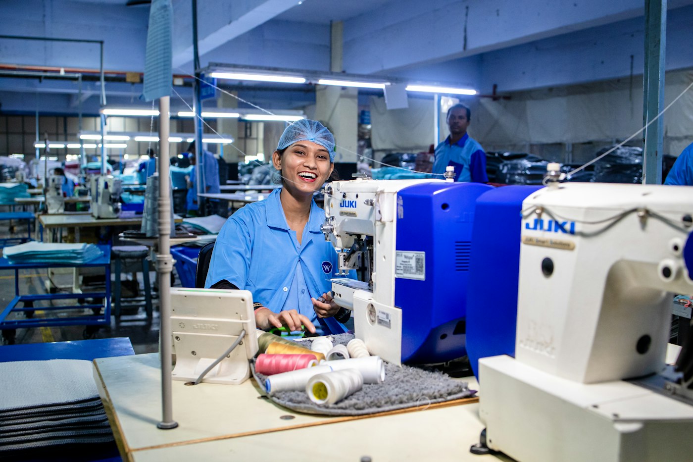 An operator smiling at her sewing station on a production floor
